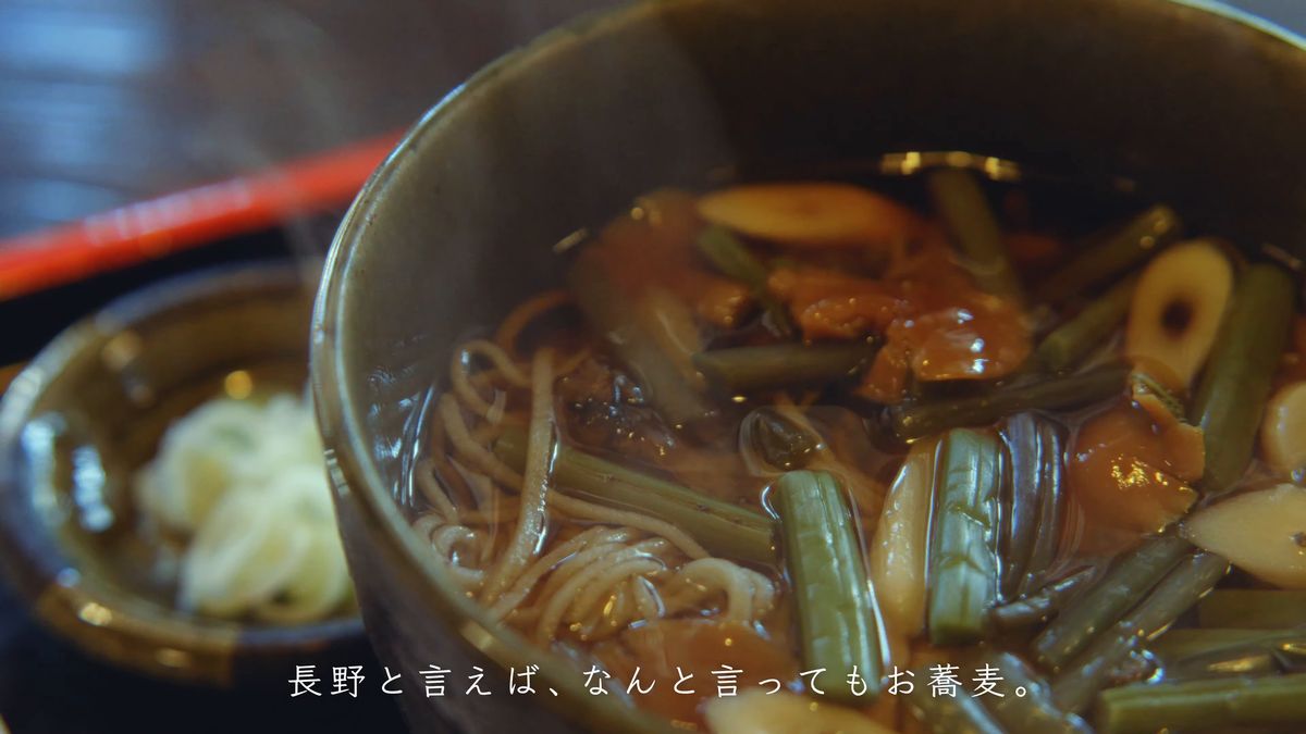 山菜とねぎがのった温かいそばの器