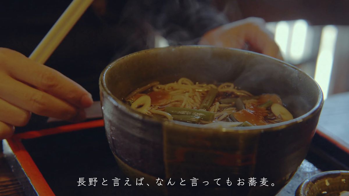 お盆の上の山菜そばに箸を伸ばす
