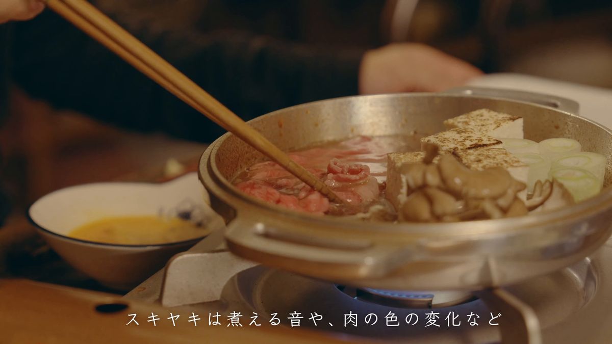 煮える鍋に牛肉を入れる箸