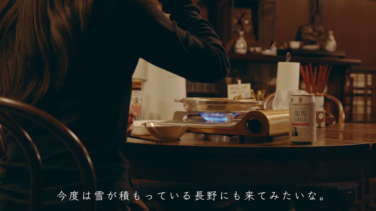 暗い部屋で卓上の鍋を前に座る後ろ姿