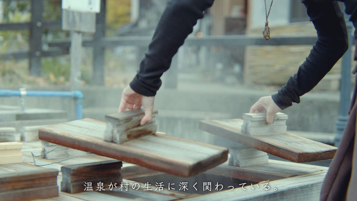 茹で場の木のふたを両手で持ち上げる