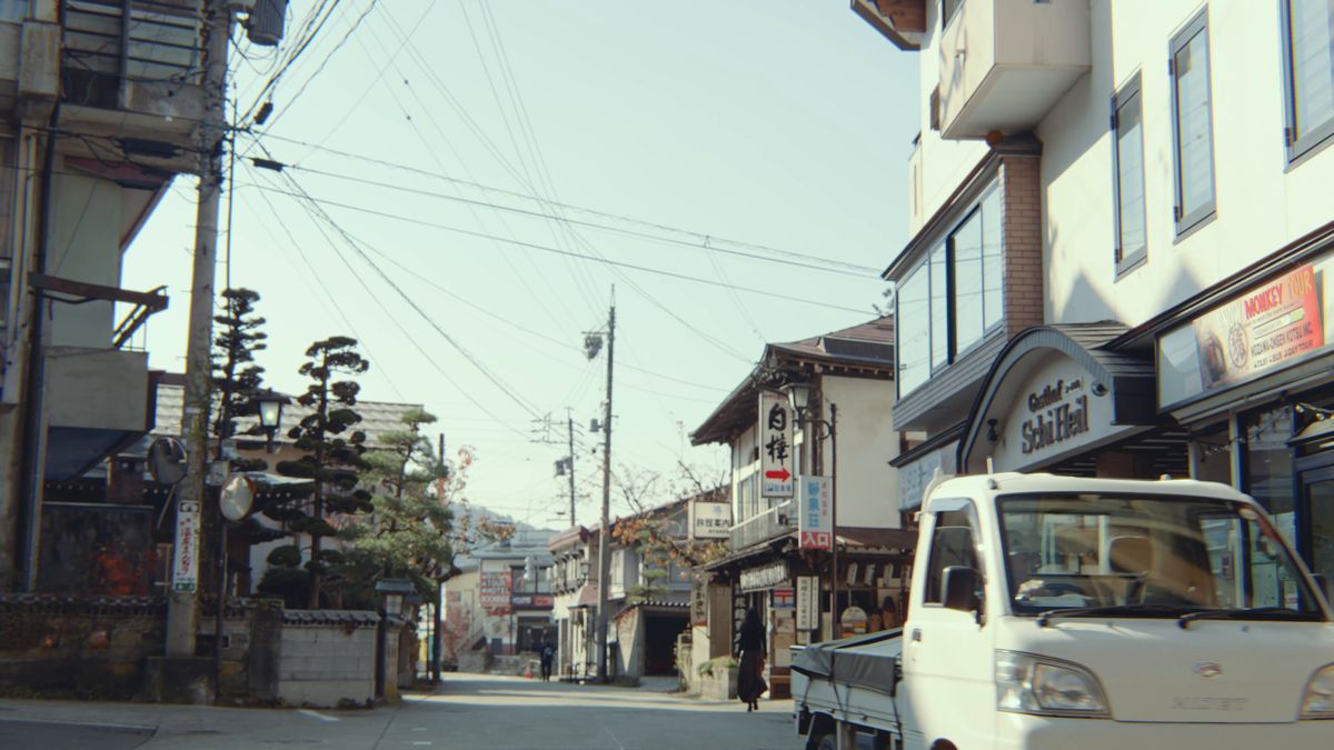 温泉街の通りに停まる白い軽トラック