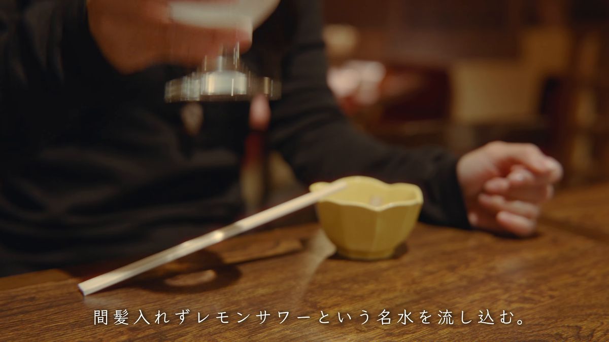 レモンサワーのグラスを手にした居酒屋の卓