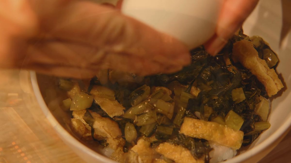 丼に温泉たまごを割り落とす手元