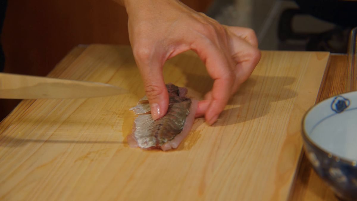 まな板の上でアジの刺身を切る