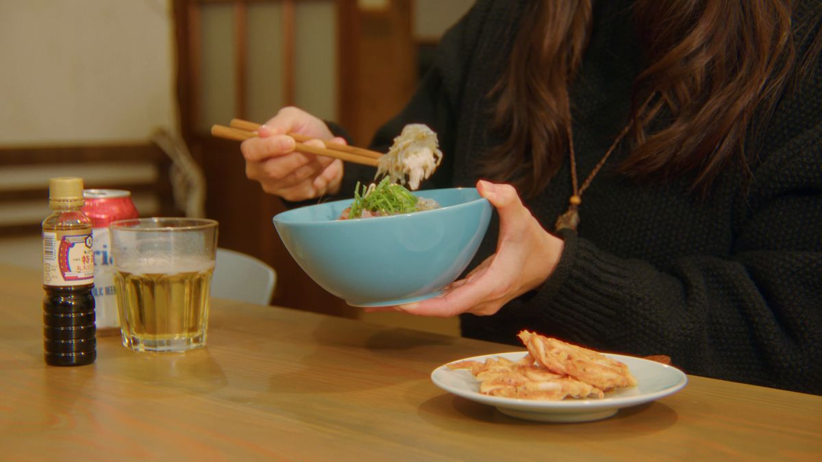 丼を手に、箸でしらすをつまむ