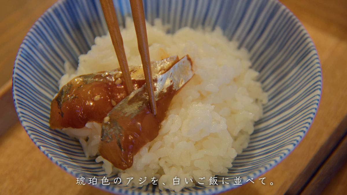 白いご飯の上に箸で醤油漬けのアジを並べる