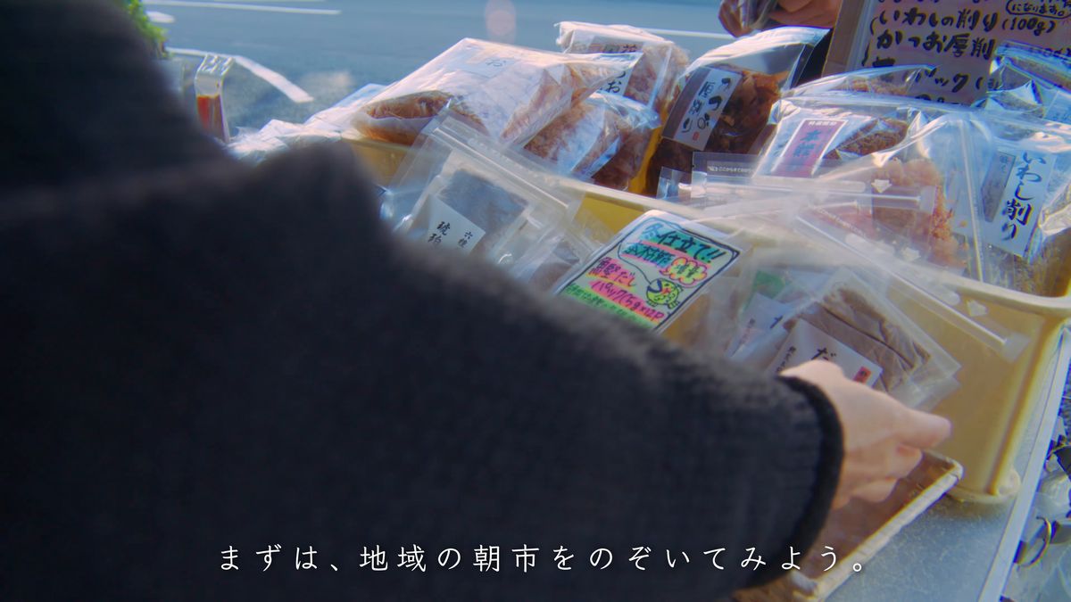 朝市の籠に並ぶ袋詰めの乾物に手を伸ばす