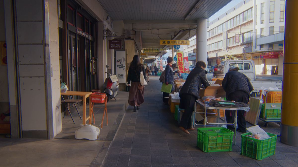 アーケードの歩道に並ぶ出店の間を歩く後ろ姿