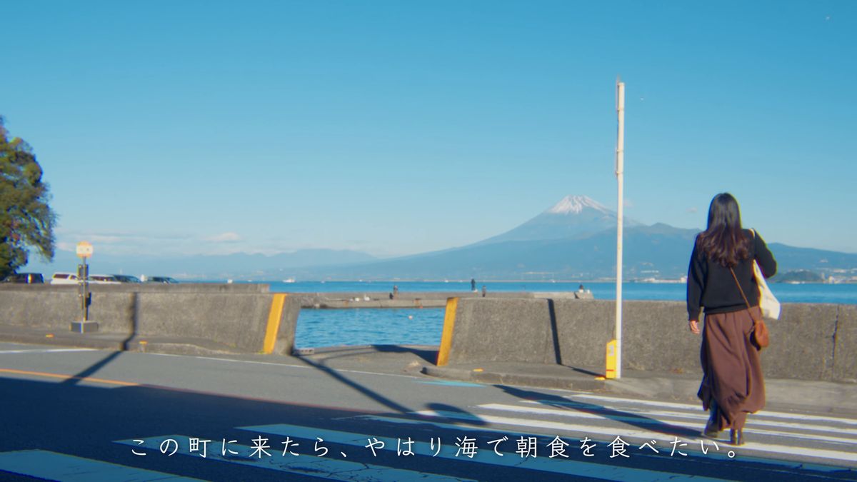 富士山に向かって海辺の道を歩く後ろ姿