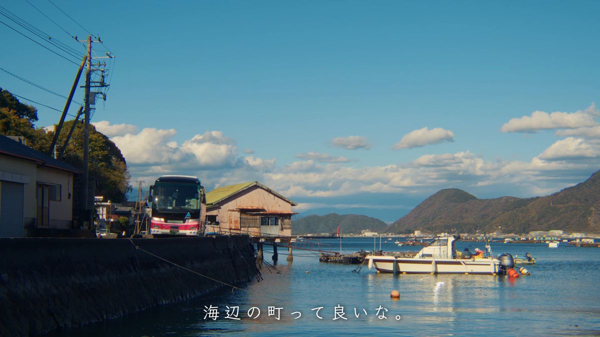 海辺の道と岸に並ぶ船、停まる観光バス