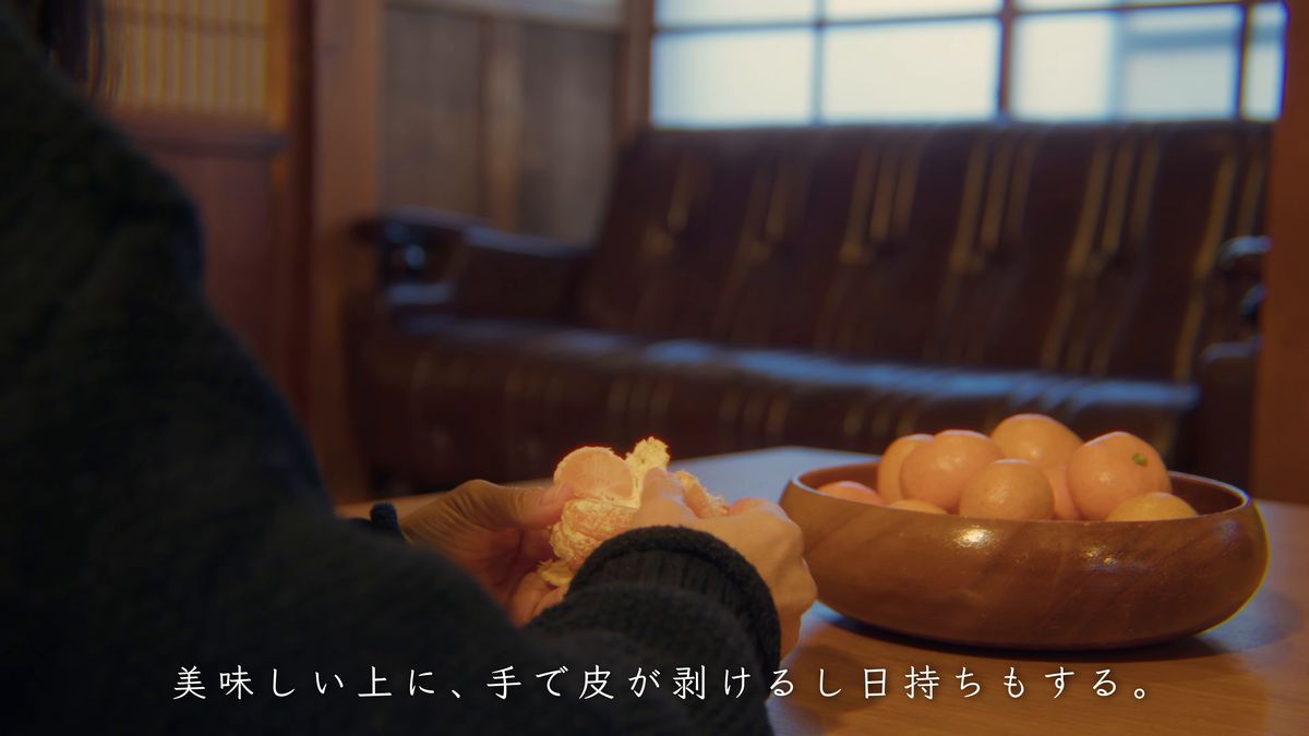 みかんの皮をむく手元とソファ