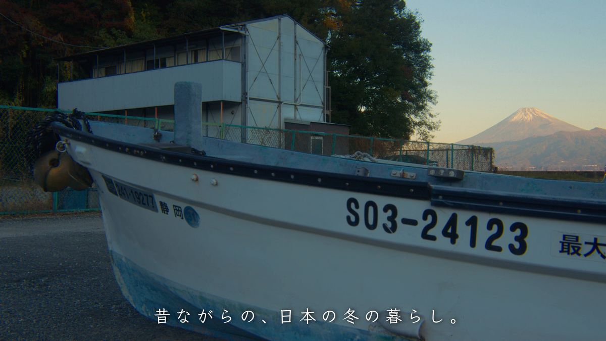 陸に上げた白い漁船の向こうに見える夕方の富士山