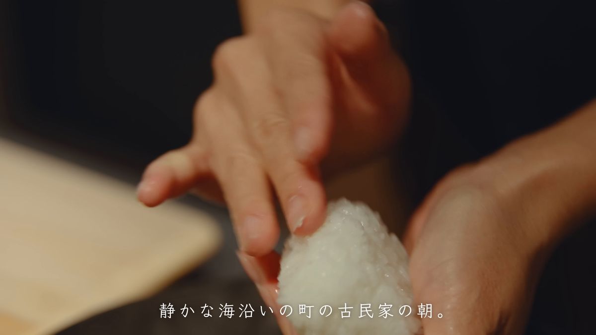 片手でおにぎりの形を整える