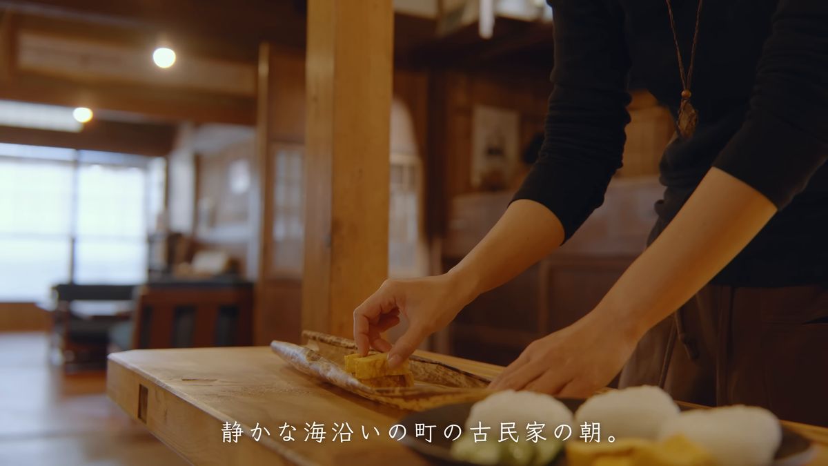 台所で竹皮の上に卵焼きを並べる後ろ姿