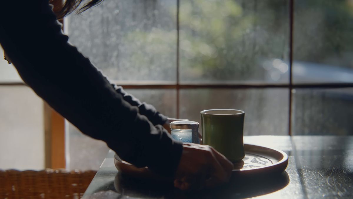 窓辺の盆にプリンの瓶とカップを置く手元