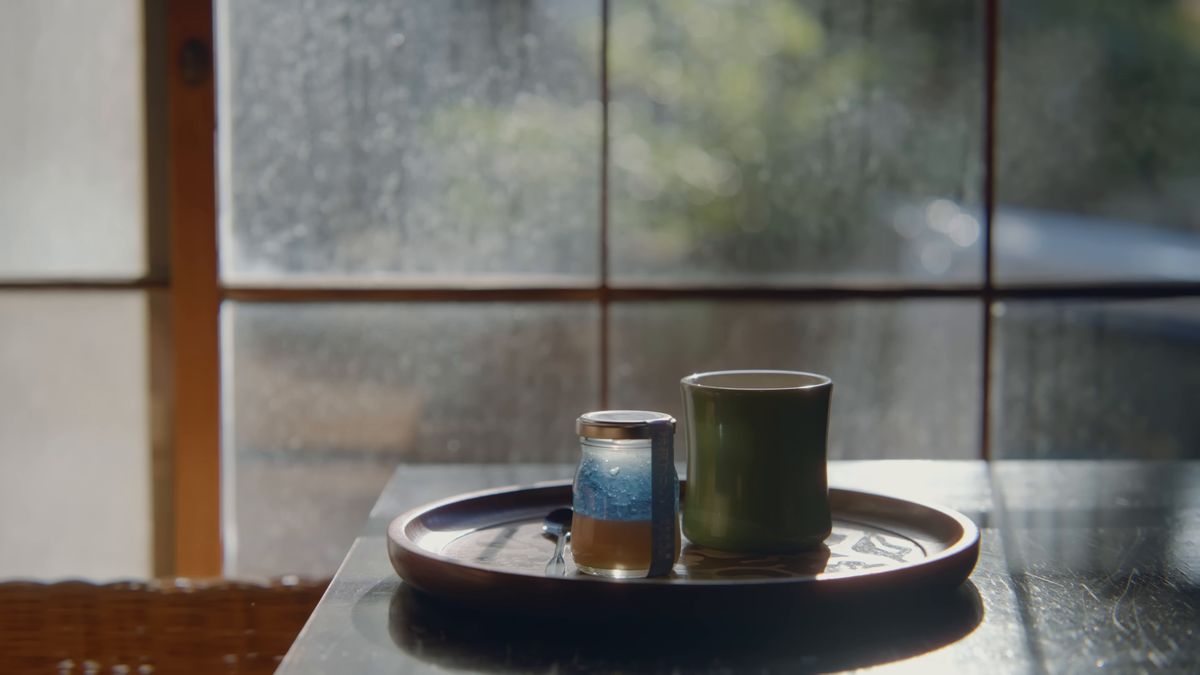 窓辺の丸い盆の上のプリンの瓶と緑のカップ