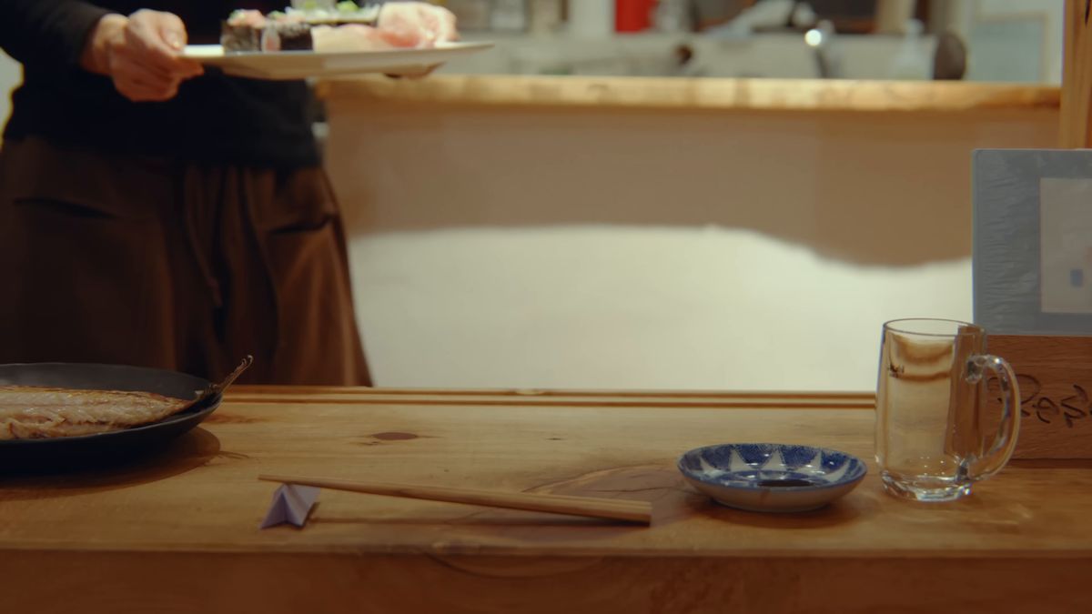 カウンター越しに寿司の皿を運ぶ