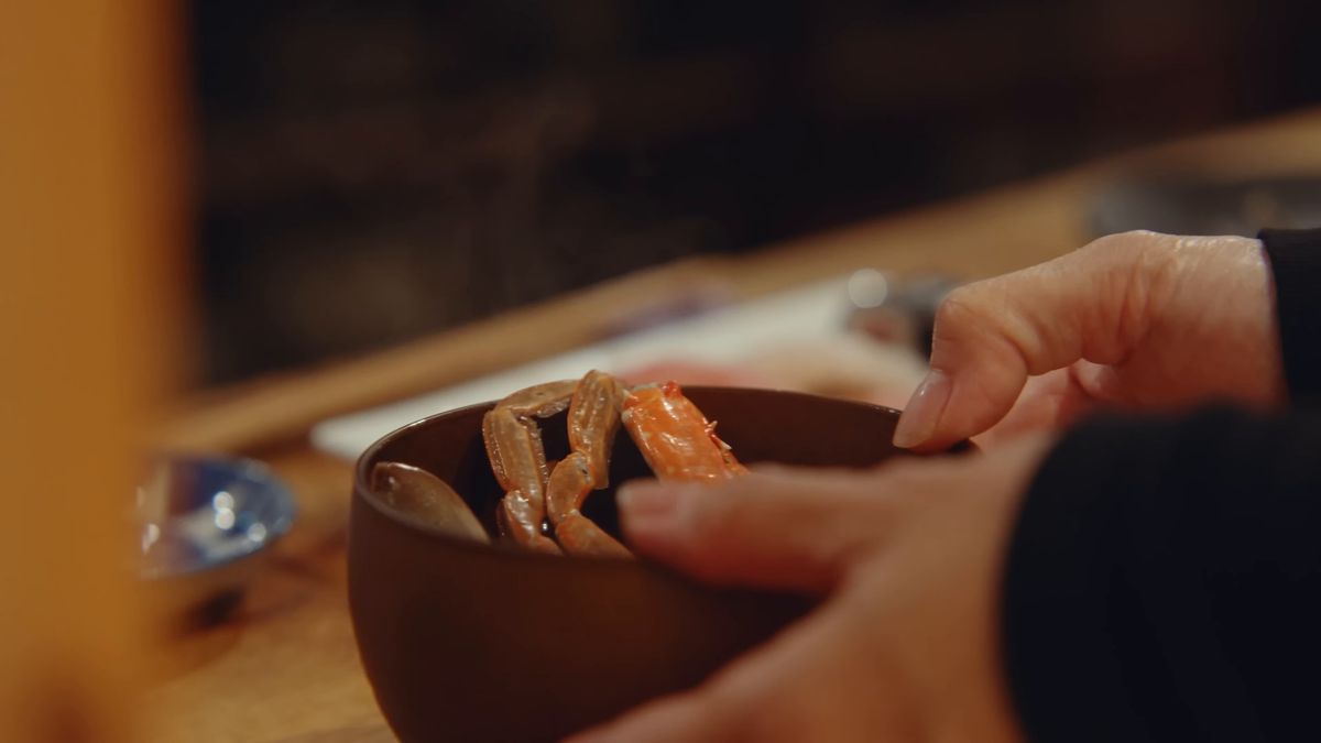 カニの入った木の椀を手にする