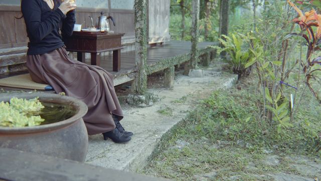 縁側に腰かけて朝ごはんを食べる後ろ姿と、緑の庭