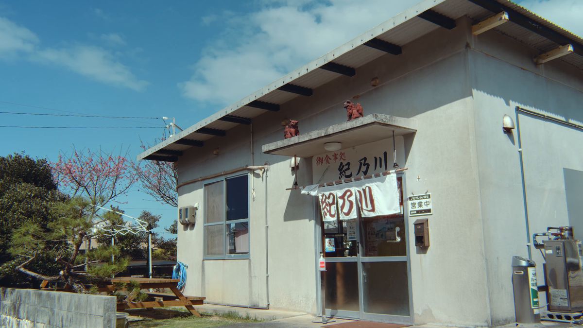 A diner entrance with shisa on the roof and a noren curtain