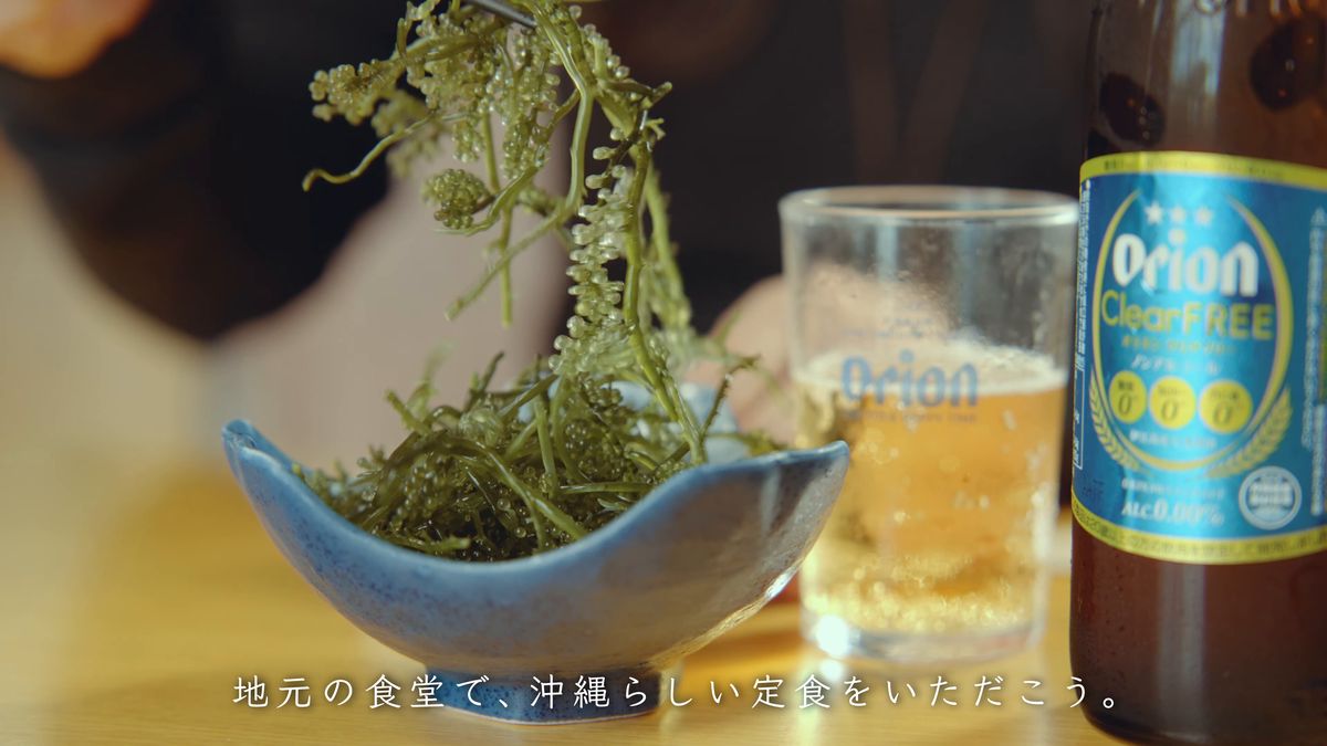 A bowl of sea grapes and a glass poured from a bottle of Orion