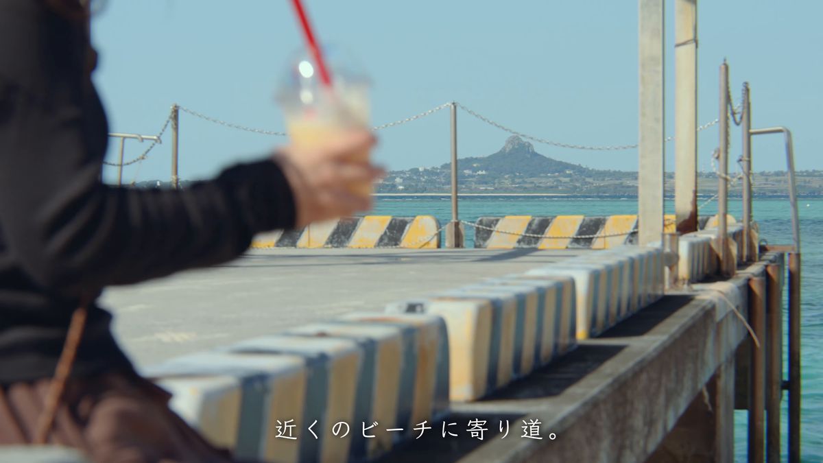 桟橋で飲み物を手に、沖の伊江島を眺める