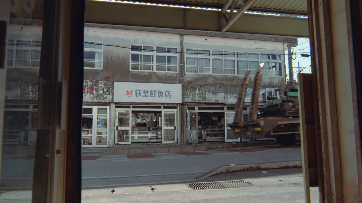 アーケードの窓越しに見える通りの向かいの鮮魚店