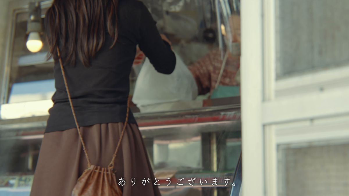 鮮魚店で包みを受け取る後ろ姿