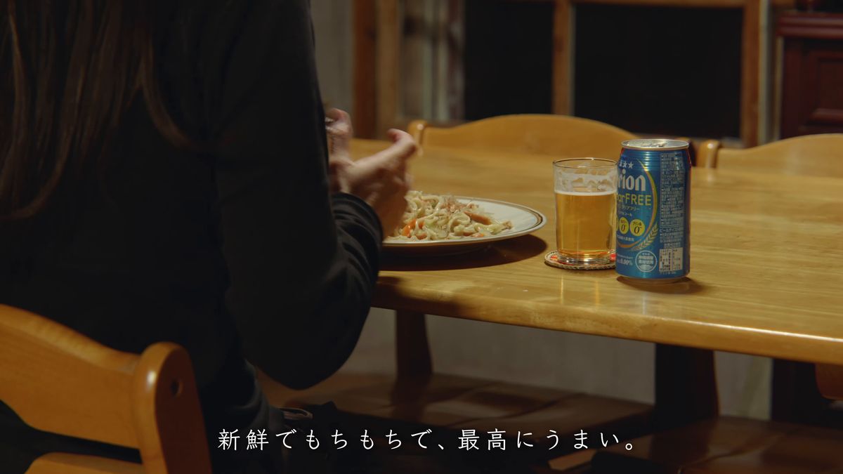 焼きそばと缶を前に食卓につく後ろ姿