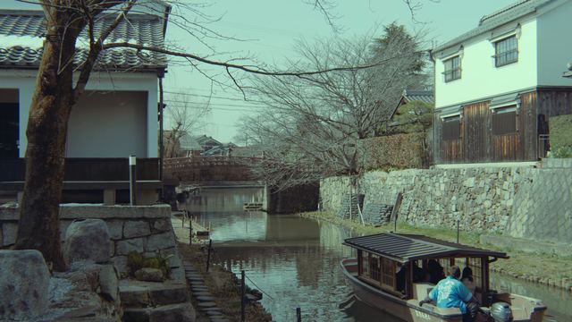 石垣と土蔵の間の八幡堀を行く和舟