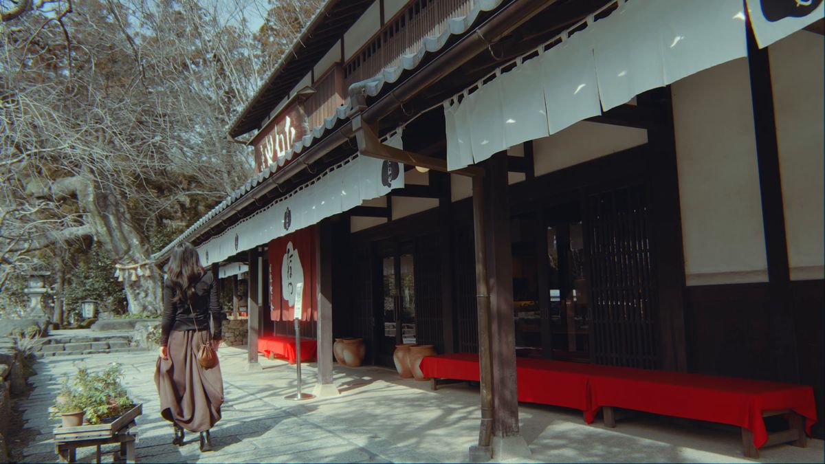 赤い縁台が続く長い軒先を歩く後ろ姿