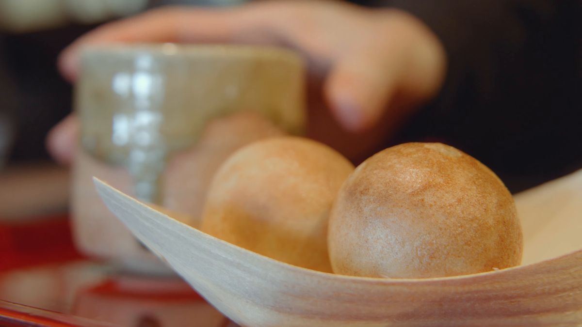 小豆茶の器を持つ手元とつぶら餅