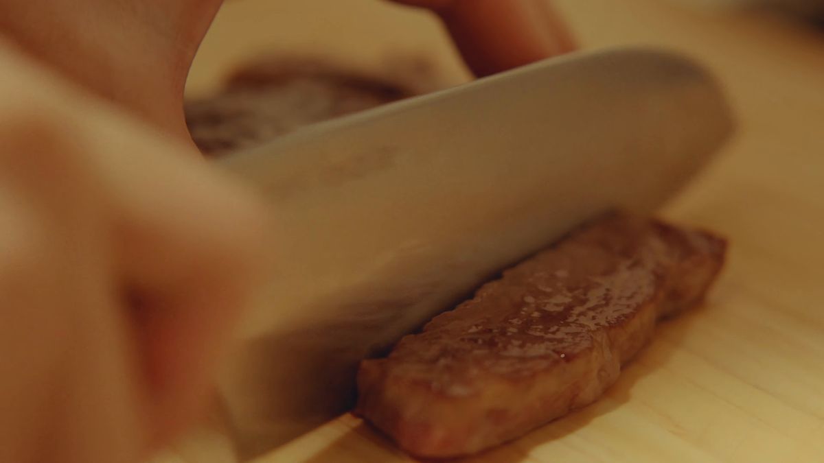 焼いた近江牛に包丁を入れる