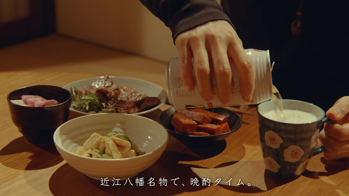 ちゃぶ台の小鉢の横でビールを注ぐ手元