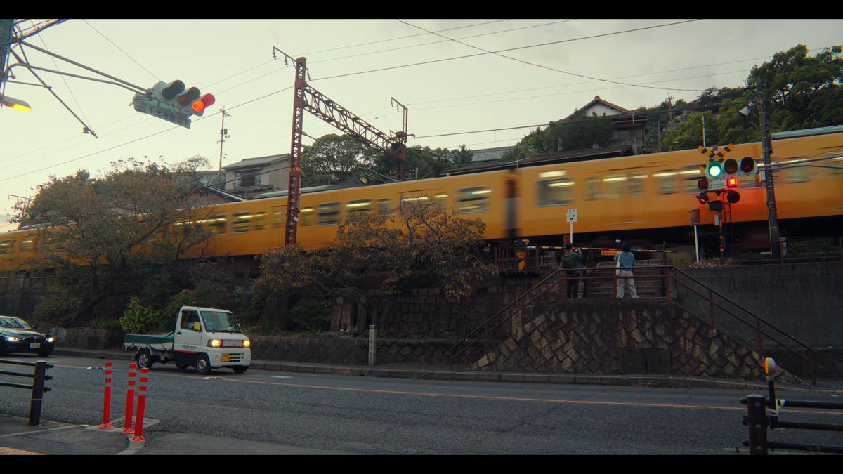 夕暮れの踏切を通り過ぎる黄色い電車