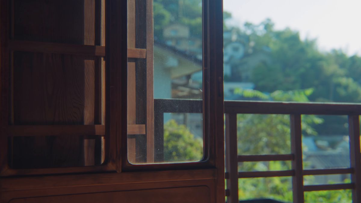 開けた窓の向こうの斜面の家々と緑