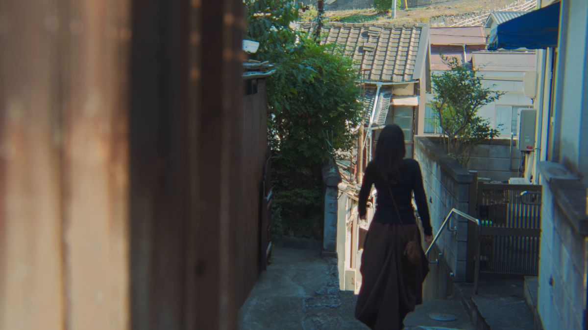家々の間の細い路地を歩く後ろ姿