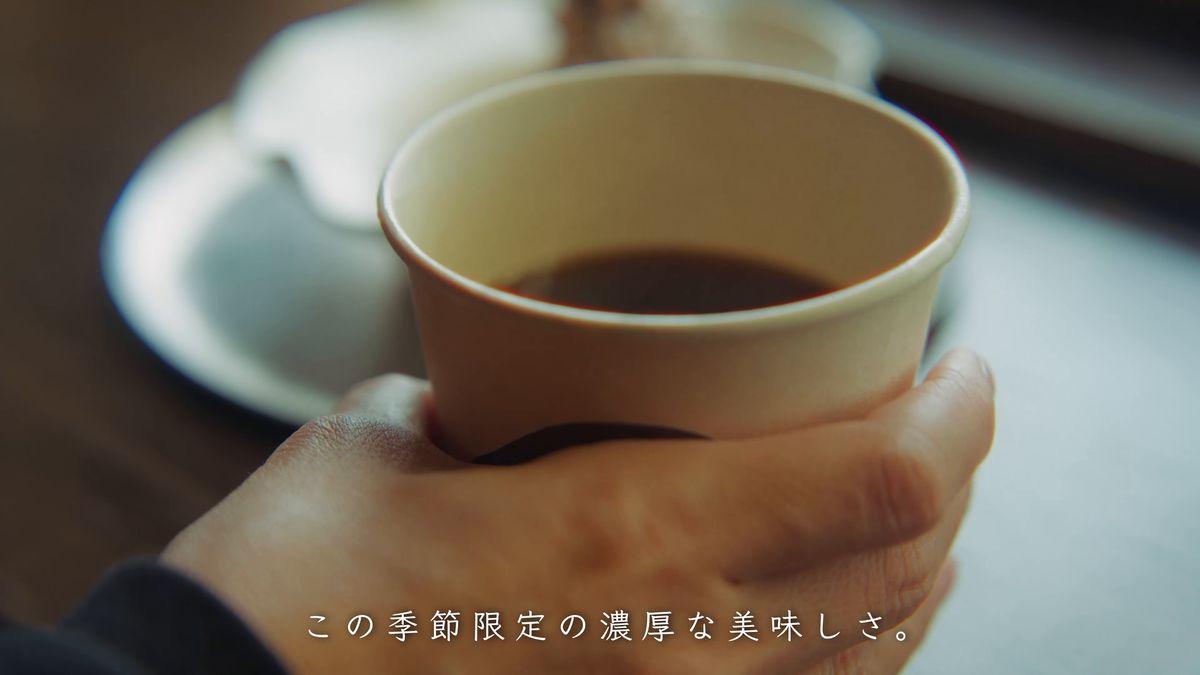紙コップのコーヒーを手に取る