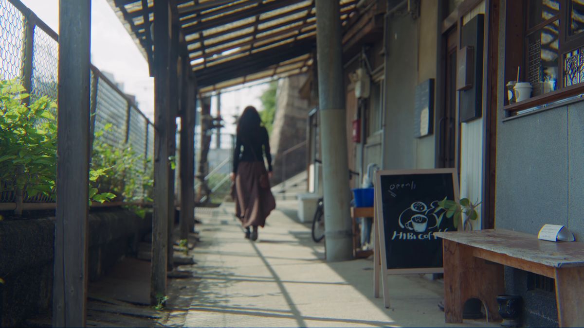 軒先のテラスを歩く後ろ姿と黒板の看板