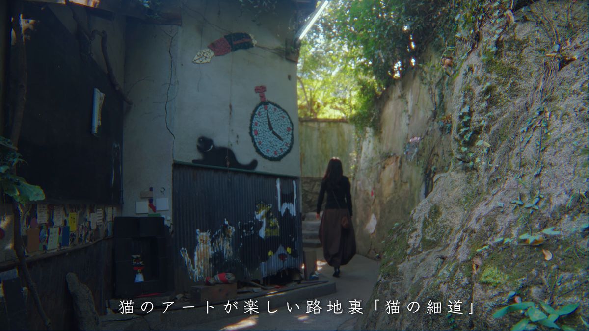時計の壁画の下の路地を歩く後ろ姿