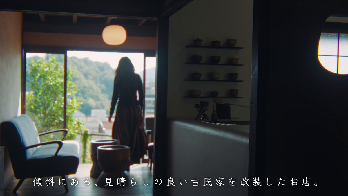 茶碗の並ぶ棚と、窓の外を眺める店内の後ろ姿