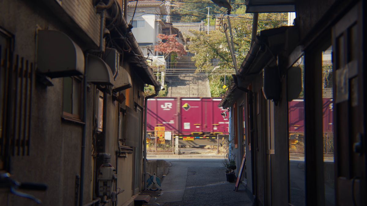 路地の奥を通る赤紫の貨物列車