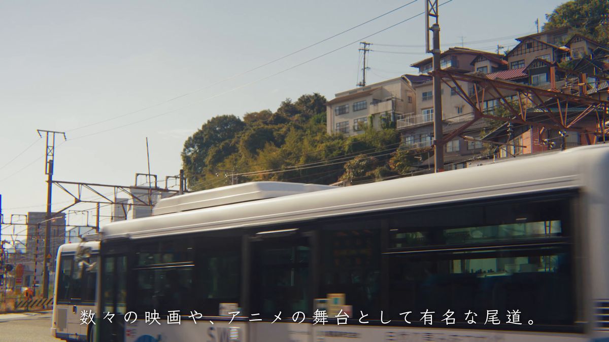 斜面に家々の並ぶ山と、通りを走るバス