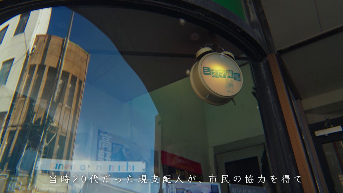 ガラス扉に映る街並みと丸い看板