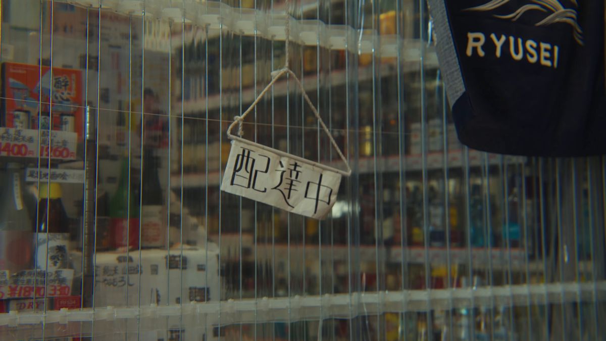 「配達中」の札がかかる酒屋のガラス戸