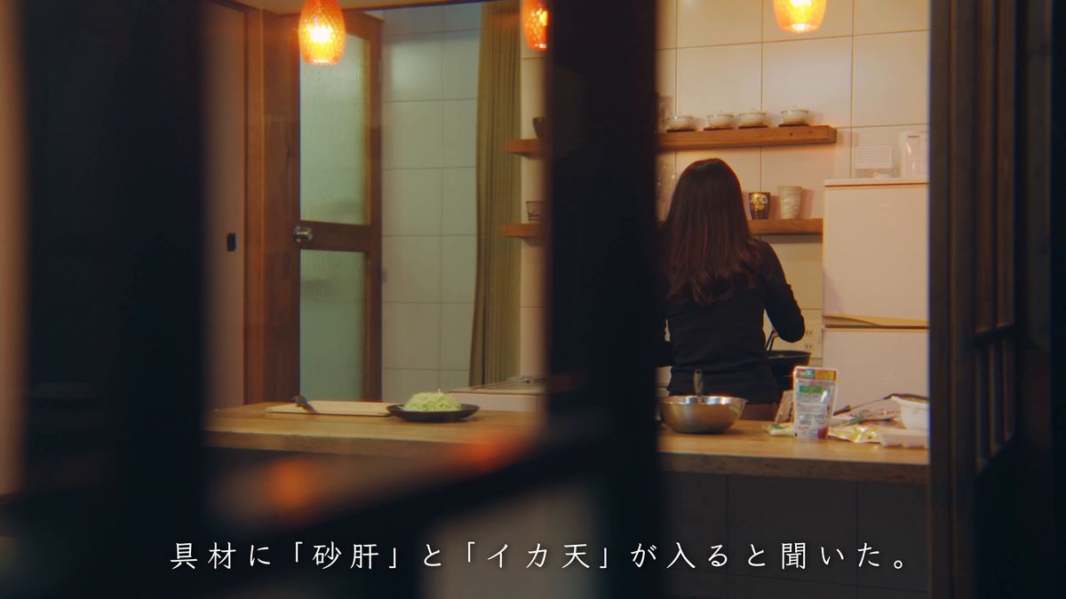明かりのついた台所に立つ後ろ姿