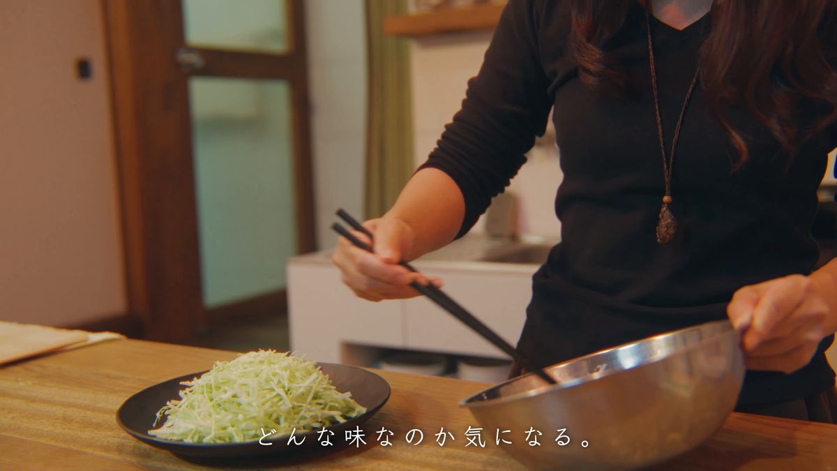 刻んだキャベツの皿を前に、ボウルで生地を混ぜる