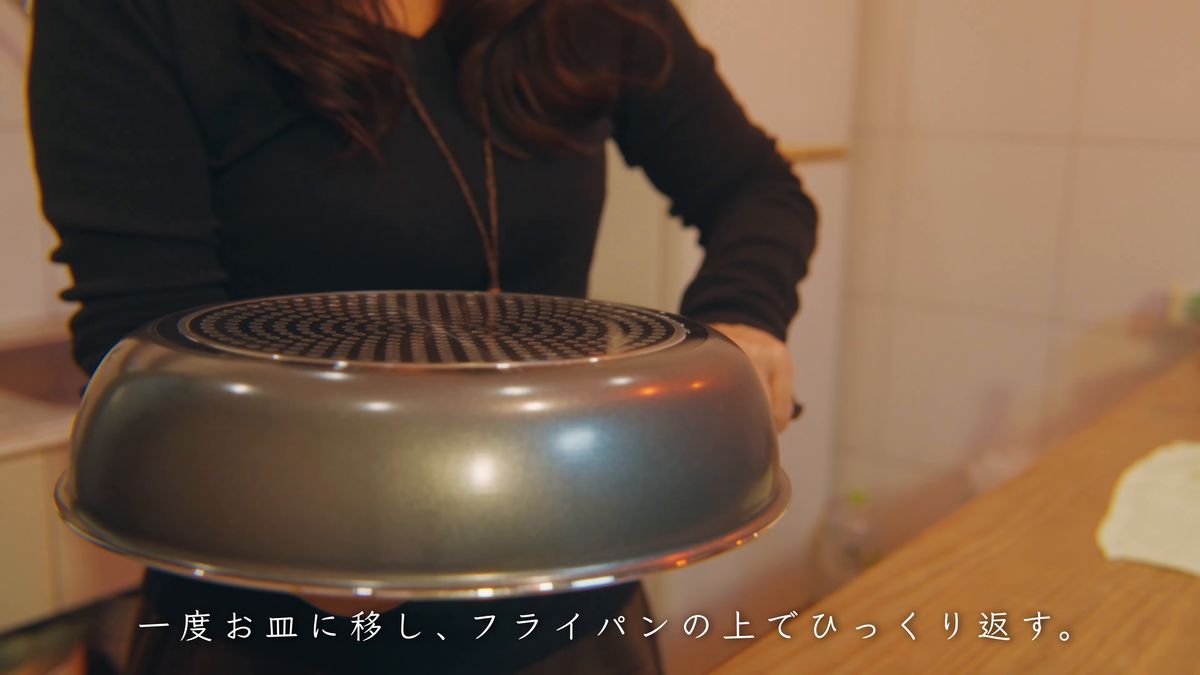 皿をかぶせたフライパンを両手で持つ