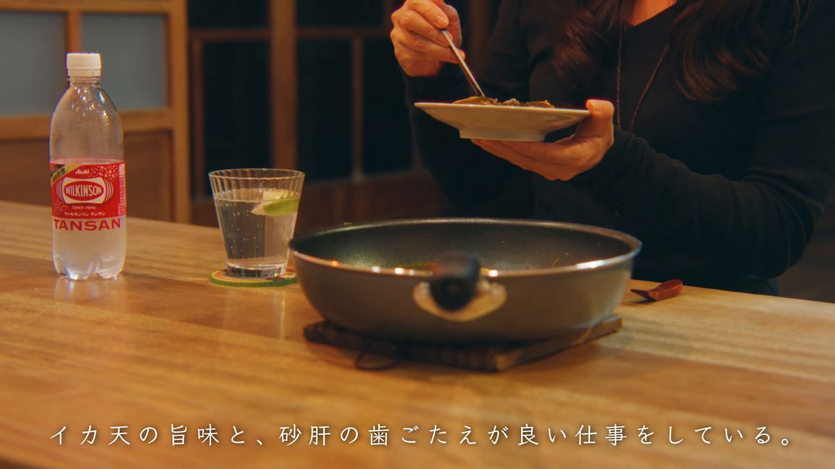 炭酸水のボトルとフライパンを前に食べる